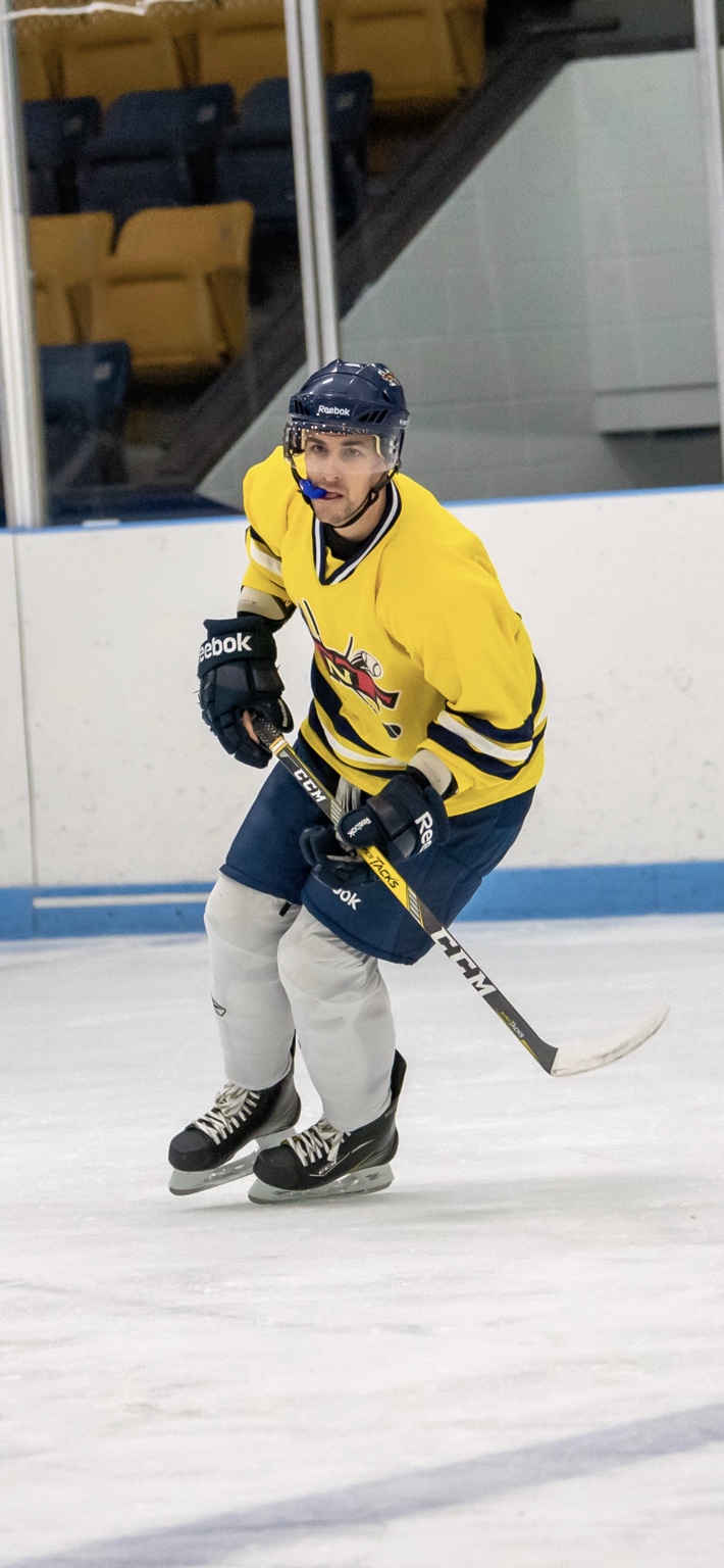 TNT Foundation hockey player in a yellow jersey skating on the ice